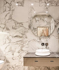 Modern bathroom with marble walls, round mirror, and sleek sink
