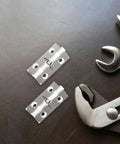 Two Pack Automatic Hidden Door Hinges With Spring Loaded Self Closing For Residential Use Concealed Crystal Clear Interior Hinges 45x35mm With Screws Sleek Modern Look For Doors And Windows next to metal tools on dark surface