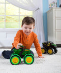 Child playing with John Deere Monster Treads Lightning Wheels Monster Truck Toy With Motion Activated Lights indoors on carpet