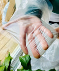 Hand showing flexibility of Clear Plastic Drop Cloths For Painting, 5 Pack 9x12 Feet Tarp Heavy Duty Waterproof Dustproof Tear Resistant.