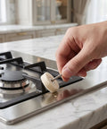 Person using mini polishing brush on stainless steel stove top to clean tight corners and restore shine.