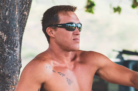 Man wearing Floating Safety Sunglasses With Matte Black Frame And Smoke Lenses, Non Slip Gray Foam Padding, ANSI Z87 Plus Certified outdoors.