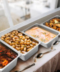 Four Pack Full Size 6 Inch Deep Steam Table Pans Stainless Steel Serving Trays For Food Service Hotels Buffets And Parties Chafing Dishes Catering Supplies filled with various foods on a table.
