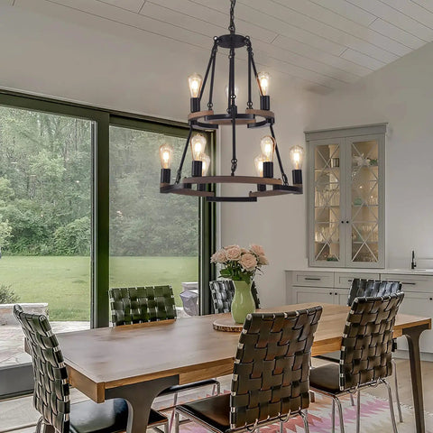 Wagon Wheel Chandelier 9 Light Farmhouse Ceiling Light in Black Metal and Wood Frame in dining room with large windows.