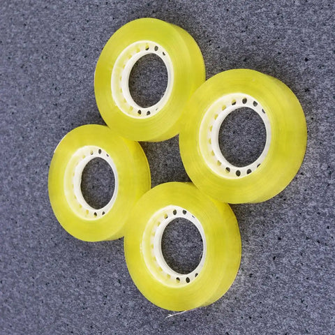 Four rolls of Dope 12 Pack 11mm X 30m BOPP Packing Tape For Packaging And School Use on a gray background