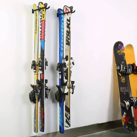 Skis and snowboard hanging on wall-mounted heavy duty garage hooks for tool organization and storage.