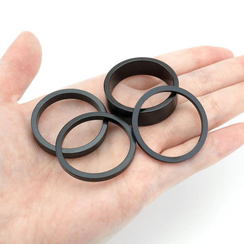 Hand holding 6 Pack 1 1/8 Inch Aluminum Bike Headset Spacers Set Anodized Black For MTB BMX Road Bikes With 2mm 3mm 5mm 10mm Shims