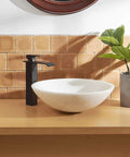 Matte Black Bathroom Vessel Sink Faucet Tall Deck Mount With Pop Up Drain beside a white vessel sink on wood vanity