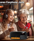 Elderly woman and young girl using Pocket Size AM FM Radio With 1200mAh Battery For All Day Power, USB and MP3 playback, red color.