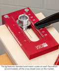 Universal Cross Dowel Jig Deluxe Kit Featuring Seven Heavy Duty Drill Guide Bushings For Bolts And Premium Wood Dowels close-up with scales on red metal base.