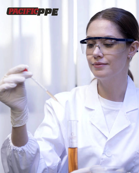 Pacific PPE safety glasses with blue wraparound frame and clear lenses in lab setting.
