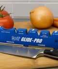 Front view of Glide-Pro All-In-One Multi Tool Blade Sharpener with ceramic stones, diamond sharpening stone, and knife on a counter.