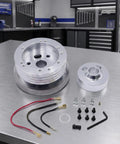 Boss Level Billet Steering Wheel Hub Adapter For 5 Or 6 Hole Whips In Sleek Silver Polish Aluminum Alloy with accessories on workbench.