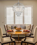 Dining room with Nine Light Crystal Chandelier With K9 Crystals, Chrome Finish, Modern Luxe Vibe, over round table and chairs.
