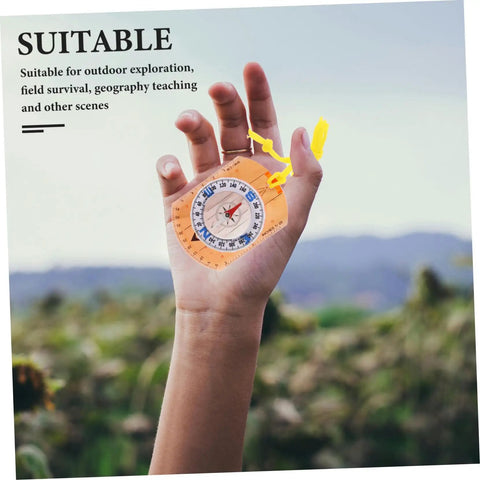 Hand holding Trail Ready Orienteering Compass with Multi Function Built In Ruler Pointer and Luminous North in outdoor setting.