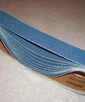 Tough As Nails 1 1/2 X 30 Inch Zirconia Sanding Belt 180 Grit 15 Pack rolled, showing flexible backing for woodworking and metal finishing.