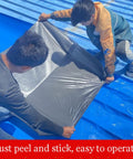 Two workers applying Rock Solid Self Adhesive Waterproof Membrane Roll on a blue roof, demonstrating easy peel and stick application.