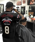 Custom Barber Smock Personalized Baseball Jersey With Staff Names And Shop Logo Sick Street Threads For Barbershops And Trendy Salons Stitched In Premium Black, worn by barber in bustling shop.