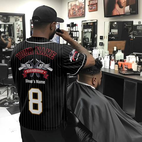 Custom Barber Smock Personalized Baseball Jersey With Staff Names And Shop Logo Sick Street Threads For Barbershops And Trendy Salons Stitched In Premium Black, worn by barber in bustling shop.