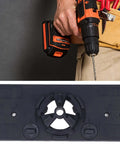 Hinge jig base plate and cordless drill, 2 items; black 35mm hinge hole saw guide shown with an orange/black drill.
