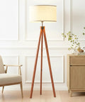Eden Tripod Floor Lamp Dimmable LED With Solid Wood Legs in a living room setting with a beige drum shade and mid-century decor