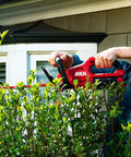 Man uses PWR Core 40 Brushless 40V Cordless Hedge Trimmer Kit With 24 Inch Dual Action Blade Three Quarter Inch Cut Capacity Includes 2.5Ah Battery And Auto PWR Jump Charger No Gas Quiet Long Lasting Power For Home Hedges to trim bushes.