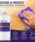 Hand using purple cloth with 32oz food-grade mineral oil for cutting boards and wood surfaces; restores and protects.