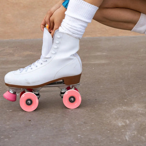 Person adjusting white roller skate with double row roller skate wheels with bearings 4 pack semi jelly outdoor wheels in pink