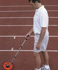 Heavy Duty Digital Measuring Wheel With Telescoping Handle And Pain Free Memory Display For Rapid Standard Or Metric Surveys in use on a track.