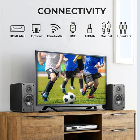 Powered Bookshelf Speakers With Wireless 100W RMS Bluetooth And EARC beside TV displaying soccer in home setup