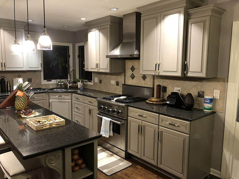Modern kitchen with granite countertops, stainless steel appliances, and grey cabinets featuring gold and black knurled bar cabinet pulls.