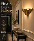 QUOLM Vintage Bronze Wall Sconce, Scalloped Uplight Wall Lamp, E26 on a wall, featuring a fan-shaped vintage bronze shade.