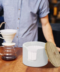 Go-To Coffee Filter Holder With Lid For Countertop Storage next to coffee preparation setup, showcasing filter organization.