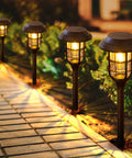Four Six Pack Color Changing Solar Garden Lights With 24 LEDs Upgraded Monocrystalline Panels illuminating a garden pathway