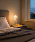 4W Dimmable Amber Globe LED Bulb With Squirrel Cage Filament, G125 Edison Style, E26 Medium Base on bedside table, warm light