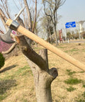 Heavy Duty Garden Pick Axe With Wooden Handle And Stainless Steel Mattock hanging on a tree in a garden setting