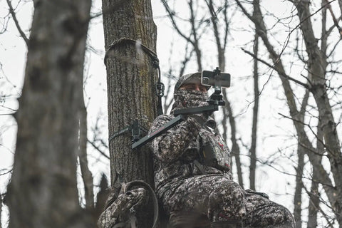 Camera Mounting Arm For Filming Hunts With Video Head No Fuss Lightweight Aluminum Build Beginner Arm For Small Cameras And Cell Phones Durable And Easy To Use Wide Range Of Motion For Smooth Shots. hunter in camo using aluminum tree-mounted camera arm with smartphone