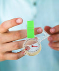 Portable Finger Compass For Hiking And Camping being held, showing its lightweight acrylic build and strap attachment for easy use.