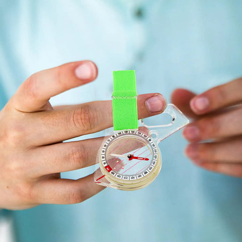 Compact Pocket Compass For Hiking And Camping, handheld direction finder in hand, durable acrylic with green strap, survival tool.