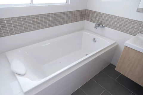 Slick Chrome Finish 27 Inch Cable Driven Bathtub Drain Trim Kit With Smooth Pop Up Stopper And Rotating Overflow Cover Brass Knob installed in a modern bathtub.
