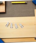 Six Piece Set Of One Inch White Nylon Sliding Roller Guide Wheels For Heavy Duty Furniture And Cabinet Drawer Tracks laid on wood surface.