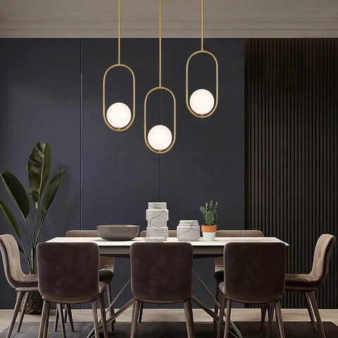 Gold Globe Pendant Light Fixture With Adjustable Hanging Length in dining room, brushed brass finish, white glass shade