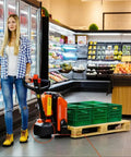 Big Budget 3300 Lb Full Electric Pallet Jack With Lithium Battery Fits Narrow Spaces with green crates in supermarket aisle.