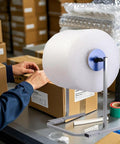 Vertical Bubble Wrap Roll Dispenser Heavy Duty Film Packing Station Foldable Cushion Holder in use at a packing station.