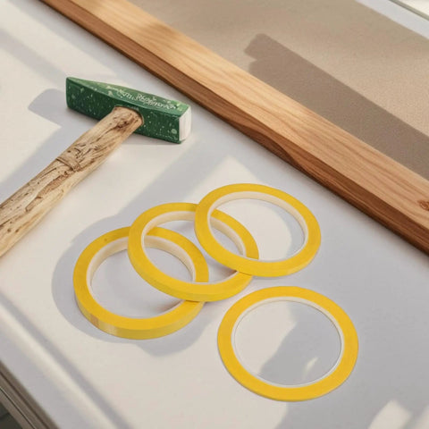 Four Pack Yellow Heat Resistant Paper Tape Featuring A Dang Tough Hold That Takes The Heat Without Breaking A Sweat on a workbench.