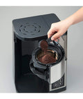 10 Cup Coffee Maker With Fresh Brew Plus Thermal Carafe Delivers Hot Coffee At 200 Degrees Fahrenheit Easy Setup For Strong Or Concentrated Ice Brew Stainless Steel And Black Finish A Real Game Changer being filled with coffee grounds.