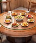 Heavy Duty Tempered Glass Lazy Susan Turntable Rock Solid Smooth Glide Kitchen Workhorse Serving Tray For Banquets And Home Tables Crystal Clear Scratch Resistant 39 Inches with several dishes on a wooden dining table.