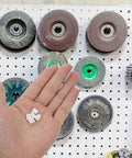 White Plastic Hole Plugs 100 Pack Screw Hole Cover Caps For Cabinets And Furniture shown in hand, pegboard background
