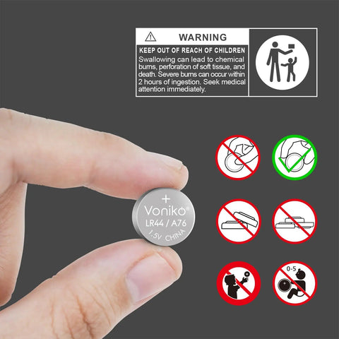 A hand holding an LR44/AG13 battery displaying warning labels for No Fuss No Muss Heavy Duty Performance Lr44 Ag13 Batteries 20 Pack Snappy 1.5 Volt Alkaline Button Cells.