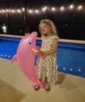 Child holding Massive 40 Inch Pearlized Dolphin Inflatable Pool Toy For Beach And Poolside Fun Pink 3 Pack Centerpiece Decor